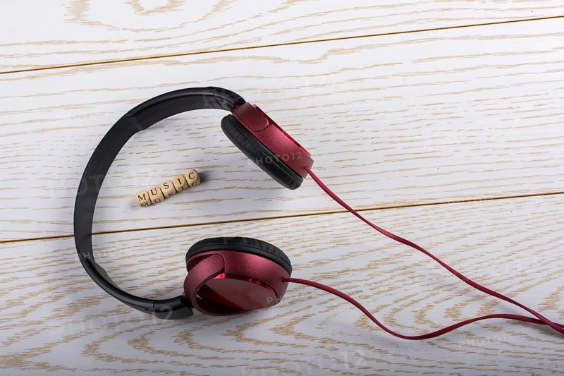 Dice-sized alphabet cubes spelling music and red headphones on wooden background