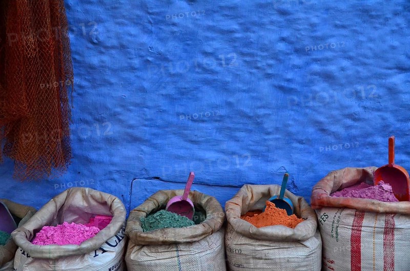 Colourful paint powder in bags in front of blue wall with shovel