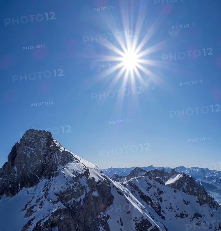Strahlende Sonne und blauer Himmel ueber Winterlandschaft und schneebedeckte Alpengipfel