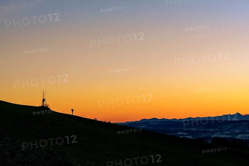 Handyfotograf bei Sonnenaufgang auf Bergruecken