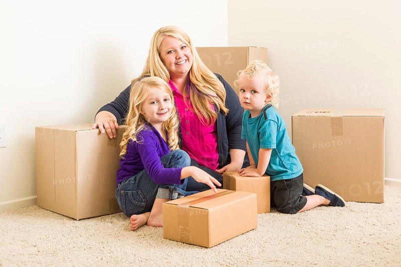 Happy young family in empty room with moving boxes