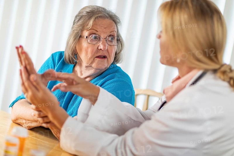 Female doctor talking with senior adult woman about hand therapy