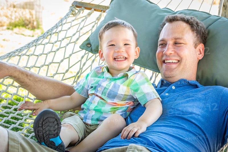 Caucasian father relaxing in hammock with mixed-race chinese son