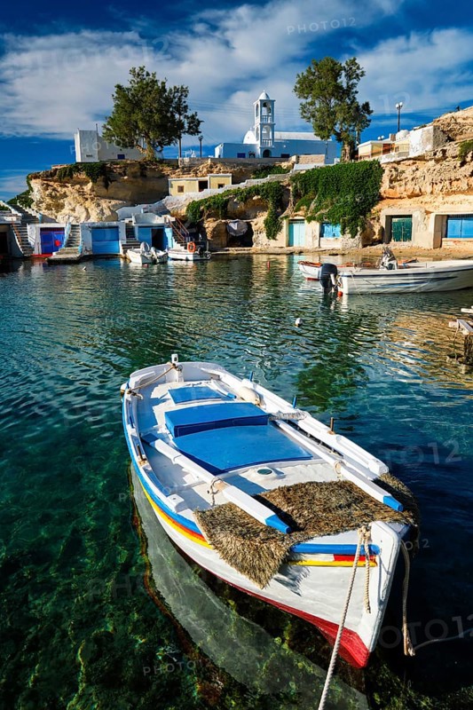 Fishing boats moored in crystal clear turquoise sea water in harbour in Greek fishing village of Mandrakia