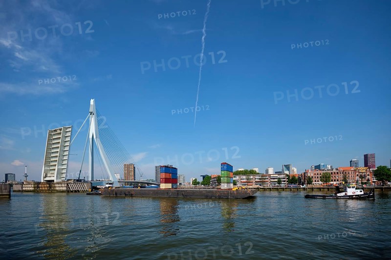 Tug boat towing barge with containers under open bascule part of Erasmusbrug bridge in Nieuwe Maas river. Rotterdam