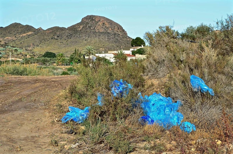 Blue crumpled plastic tarp at the edge of a field