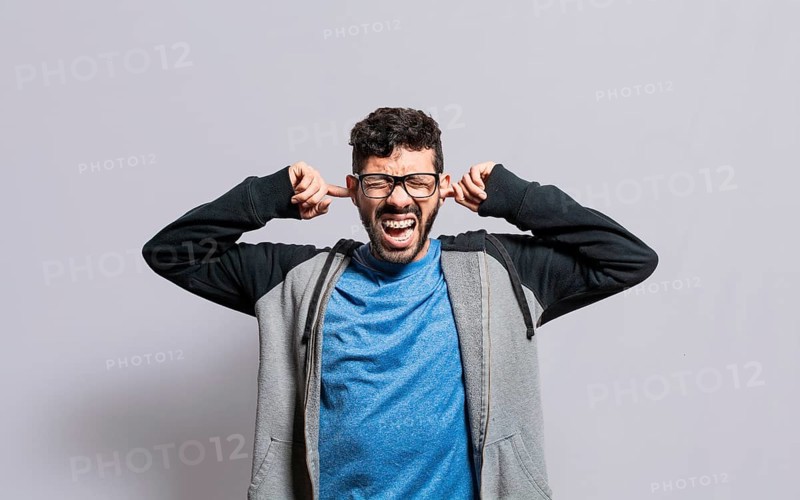 Irritated person screaming covering his ears
