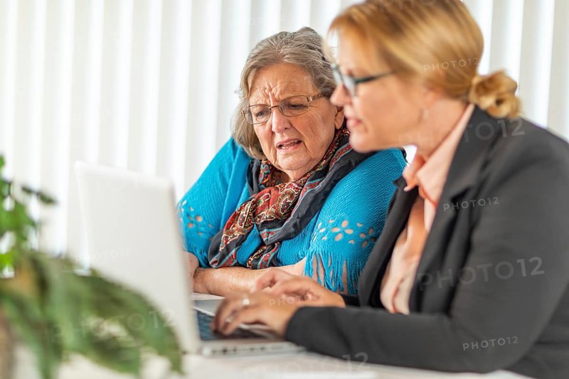 Woman helping senior adult lady on laptop computer
