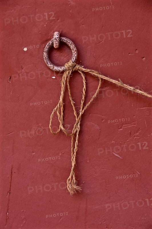 Metal ring on red wall with tied long cord