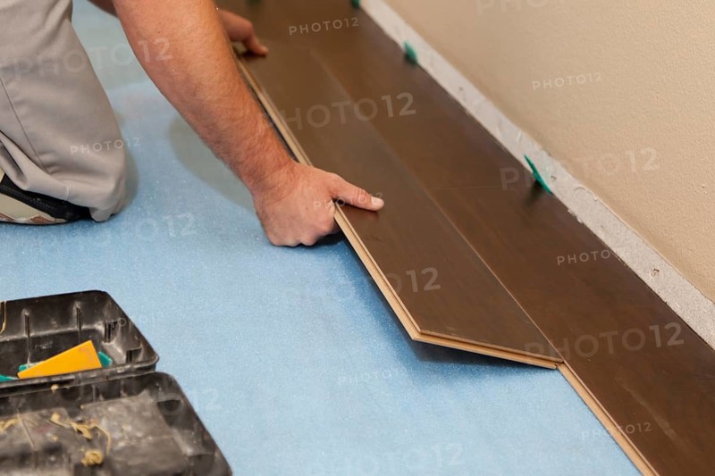 Man installing new laminate wood flooring abstract