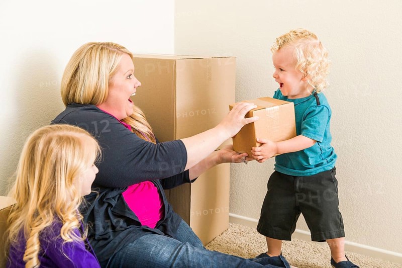 Playful young family in empty room playing with moving boxes