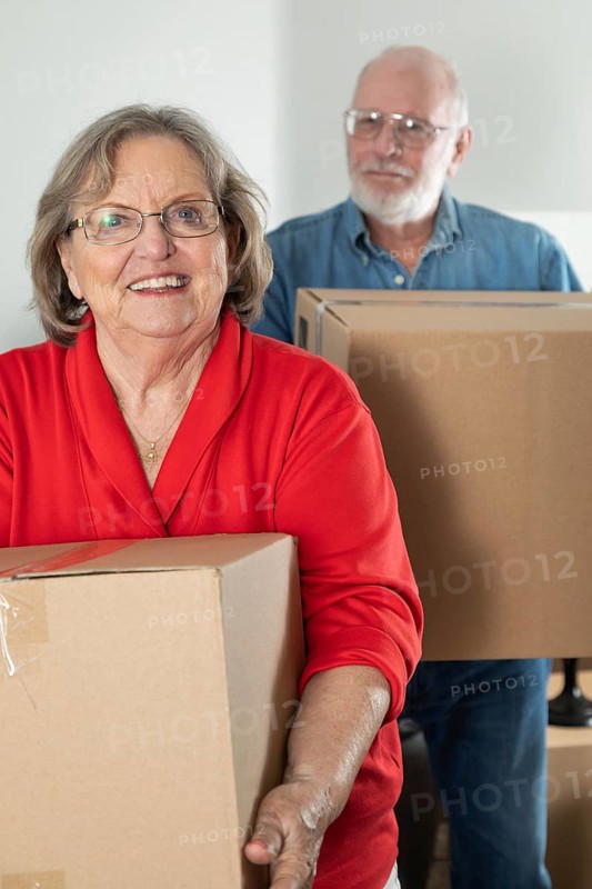 Senior adult couple carrying moving boxes