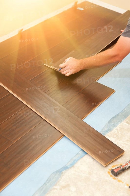 Man installing new laminate wood flooring abstract