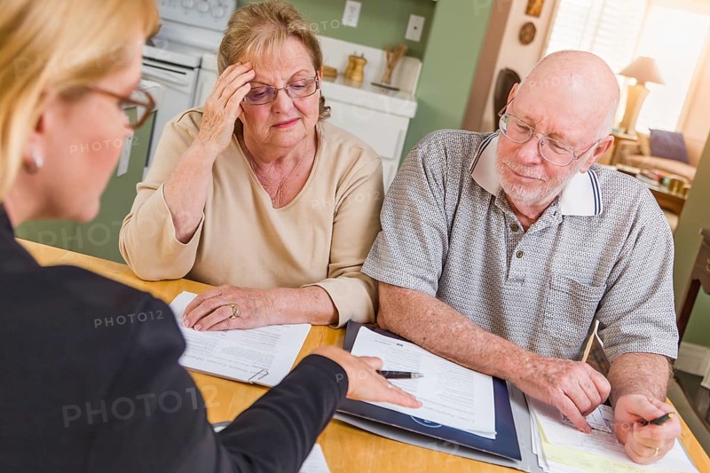 Senior adult couple going over documents in their home with agent at signing