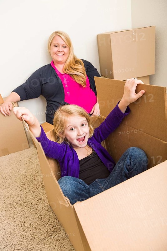 Playful young family in empty room playing with moving boxes