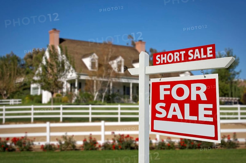 Short sale home for sale real estate sign in front of new house