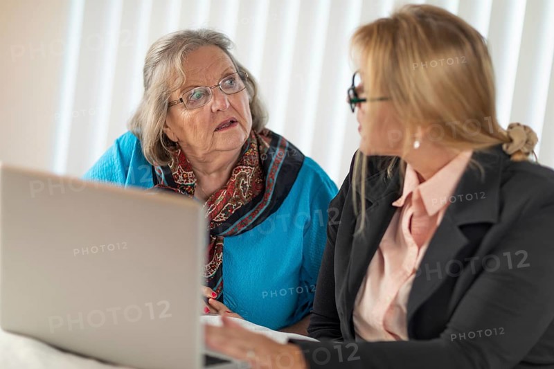 Woman helping senior adult lady on laptop computer