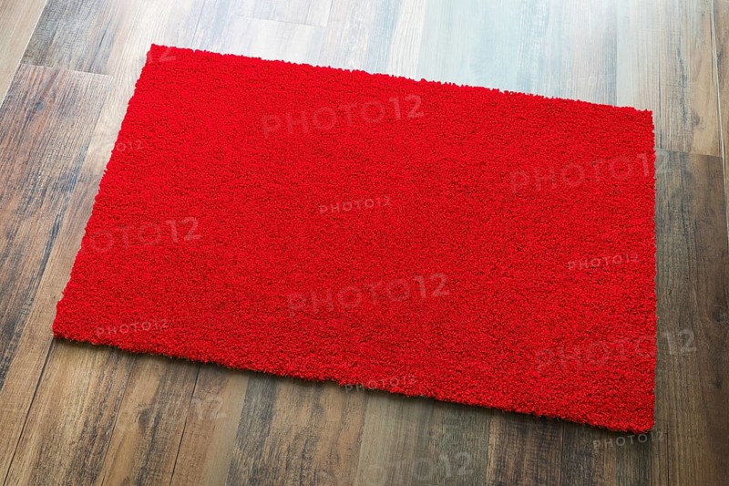 Blank red welcome mat on wood floor background ready for your own text