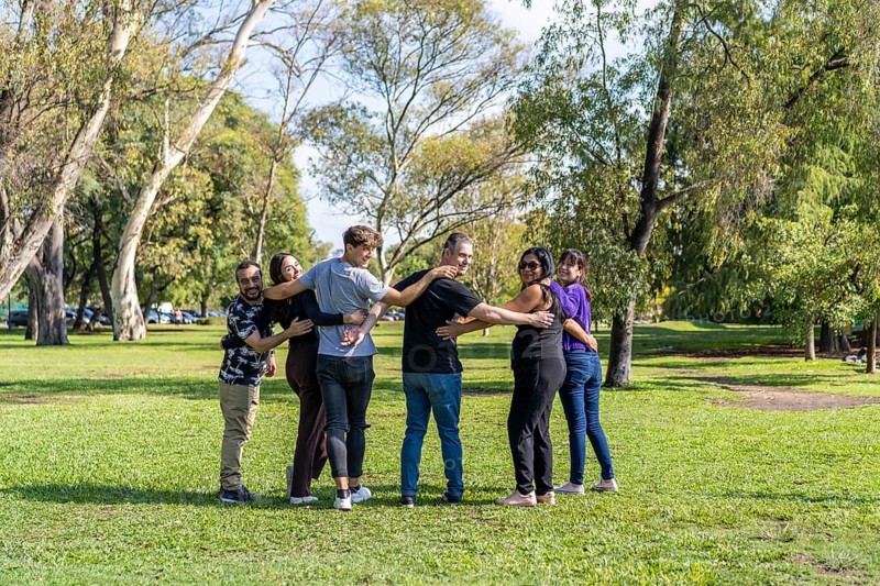 Multi ethnic family group walking arm in arm in a park
