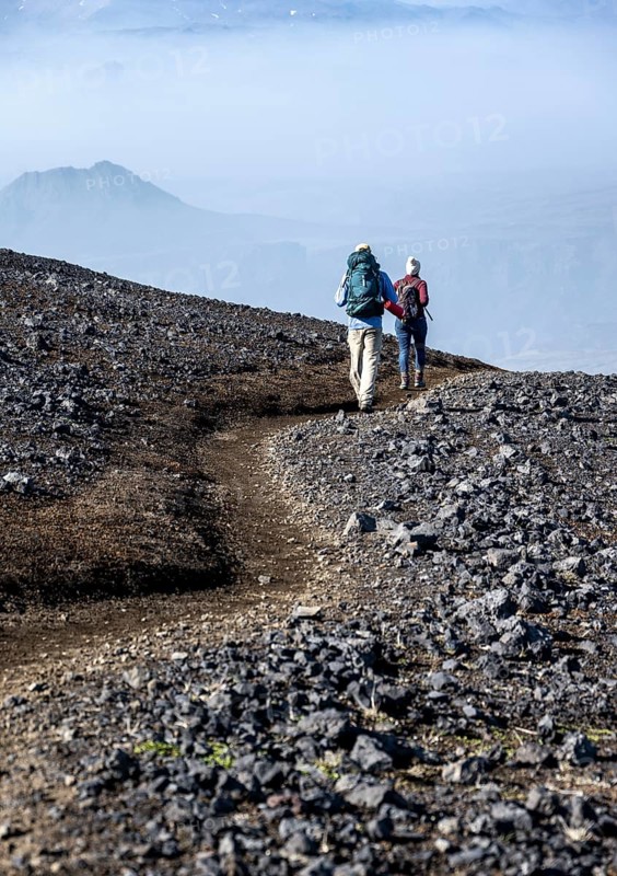 Two hikers on trail through volcanic landscape