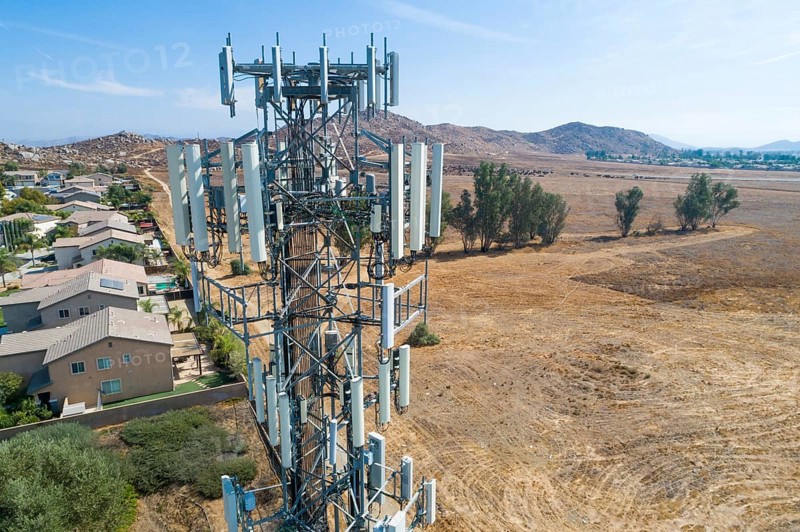 Close-up aerial of cellular wireless mobile data tower with neighborhood surrounding