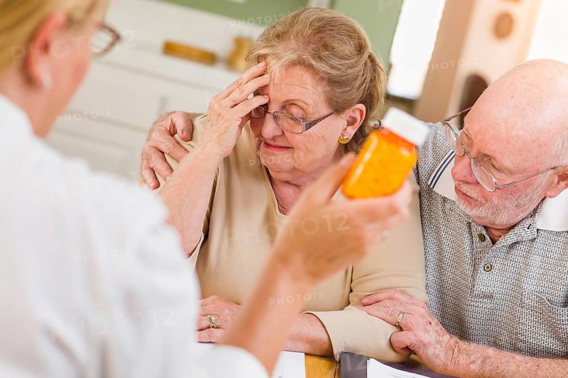 Doctor or nurse explaining prescription medicine to senior adult couple