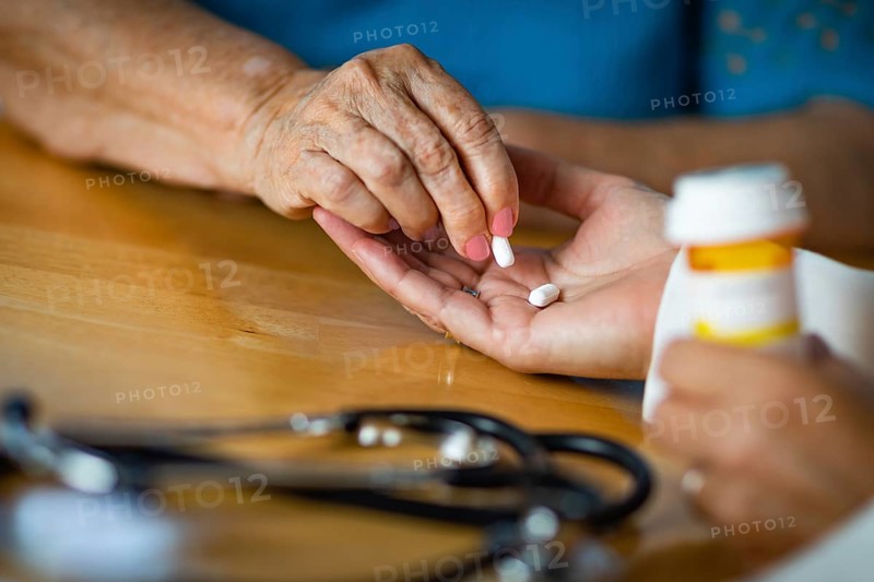 Senior adult woman taking medicine pill from doctors palm