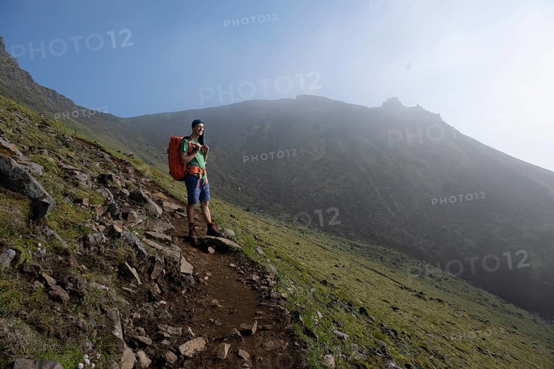Hikers on trail through moss-covered mountain landscape