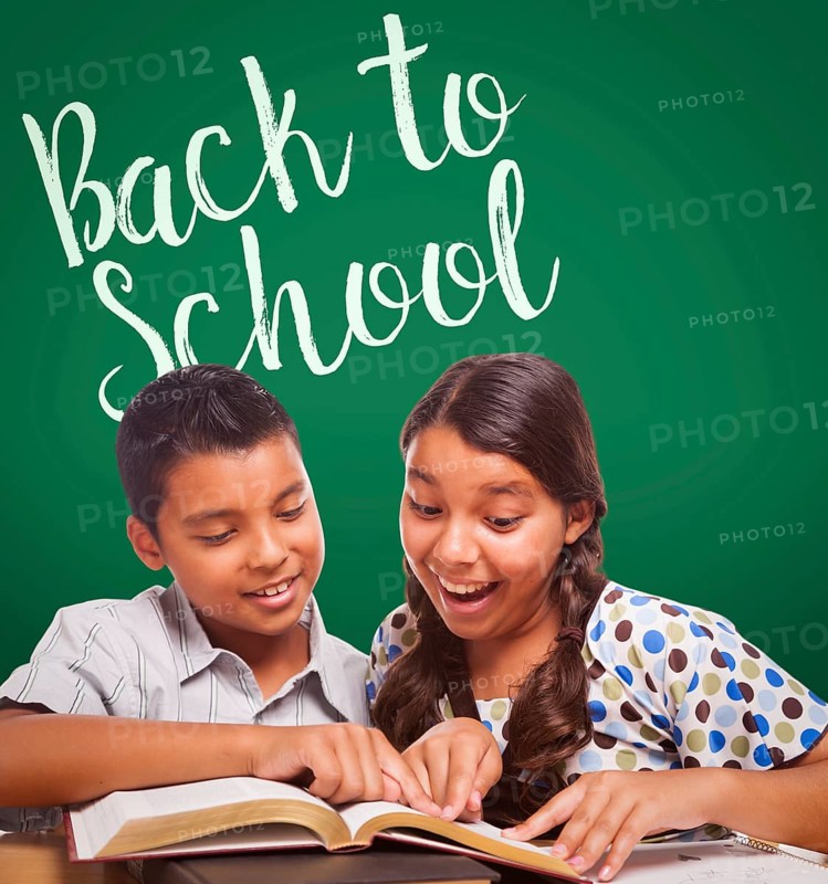 Back to school written on chalk board behind hispanic boy and girl having fun studying together
