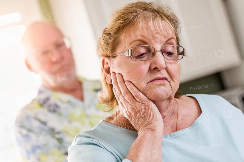 Senior adult man standing behind sad senior adult female