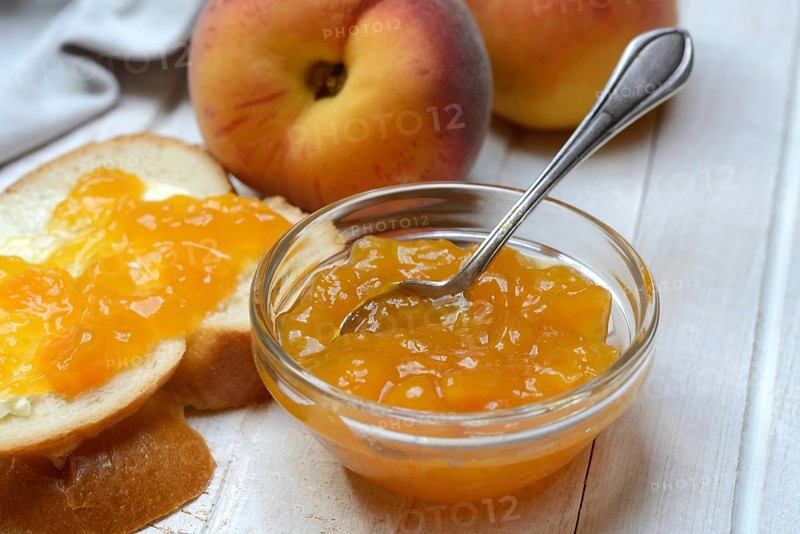 Peach jam in a glass bowl with spoon