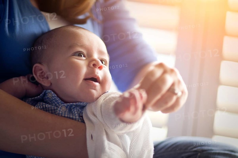 Happy mixed-race couple enjoying their newborn son in the light of the window