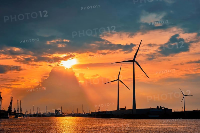 Wind turbines power electricity generators in Antwerp port on sunset