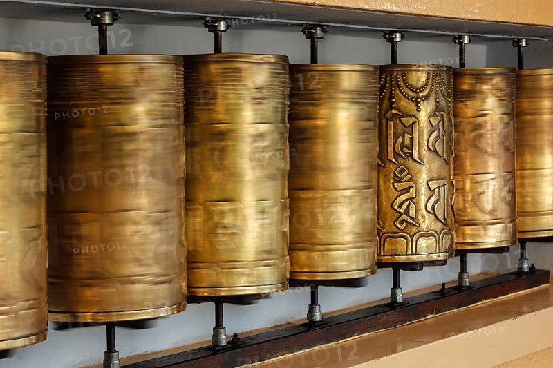 Rotating motion blurred metal buddhist prayer wheels with Om Mani Padme Hum mantra meaning Praise to Jewel in Lotus in Tsuglagkhang complex in Dalai Lama residence