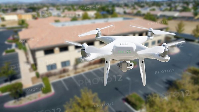Unmanned aircraft system quadcopter drone in the air near corporate industrial building