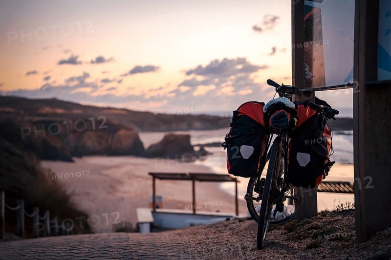 Bicycle with bags by the Almograve beach at sunset