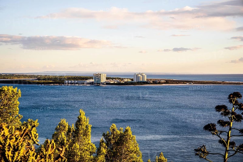 Cityscape of Troia by sunset with Atlantic ocean and trees in the foreground