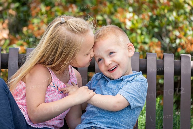 Young sister and brother having fun on the bench at the park