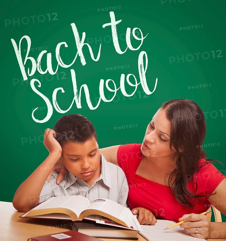 Back to school written on chalk board behind hispanic young boy and famale adult studying
