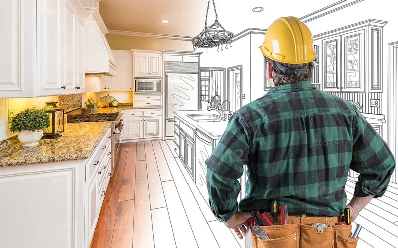 Male contractor with hard hat and tool belt looking at custom kitchen drawing photo combination on white