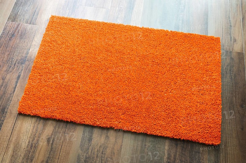 Blank orange welcome mat on wood floor background ready for your own text