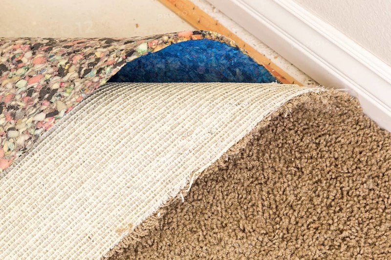 Pulled back carpet and underlayding in room of house