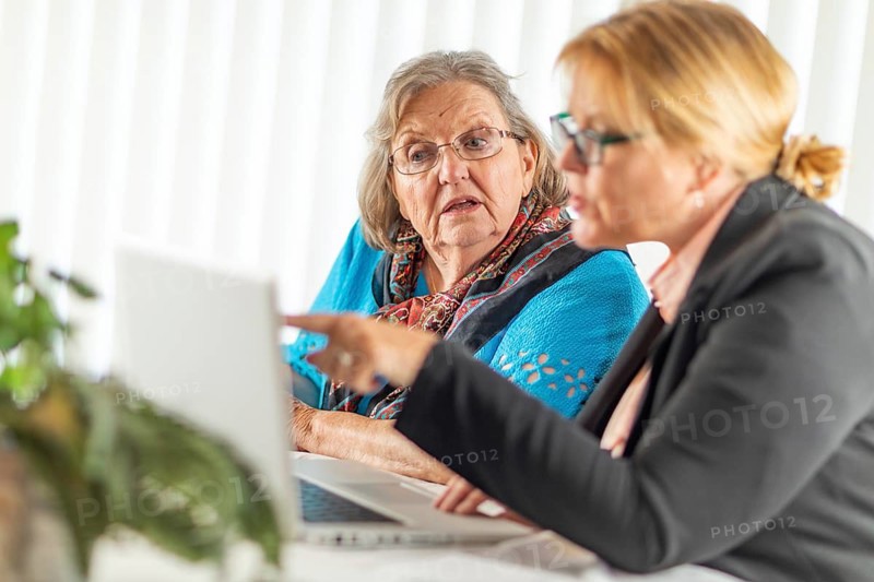 Woman helping senior adult lady on laptop computer