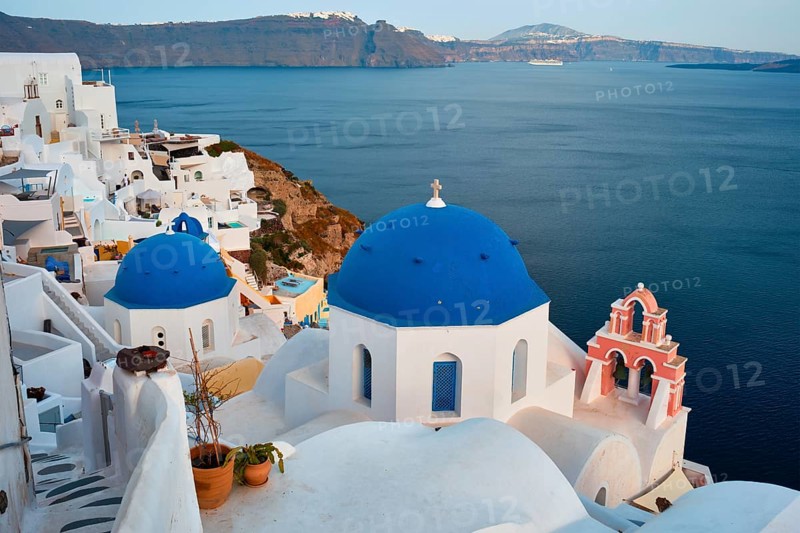 Famous view from viewpoint of Santorini Oia village with blue dome of whitewashed greek orthodox Christian church of traditional greek architecture