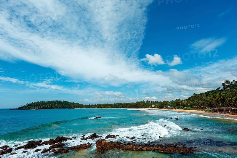 Mirissa beach in Sri Lanka in daytime with clouds and waves in sea