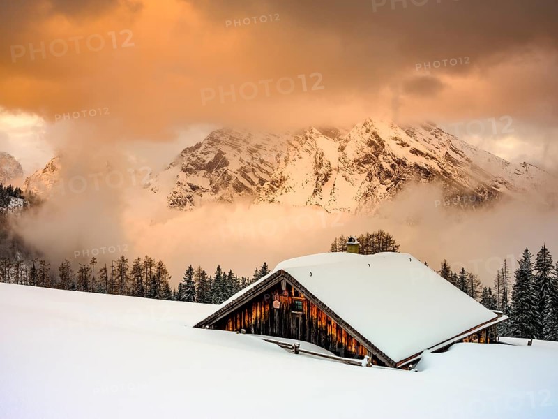 Snow-covered Priesbergalm in front of cloud-covered Watzmann