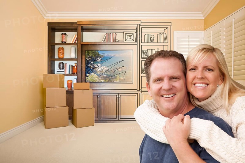 Young couple in room with moving boxes and drawing of entertainment unit on wall