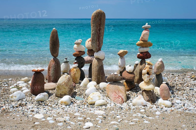 Concept of balance and harmony. Stones pebbles stacks on the beach coast of the blue sea in the nature. Meditative art of stone stacking