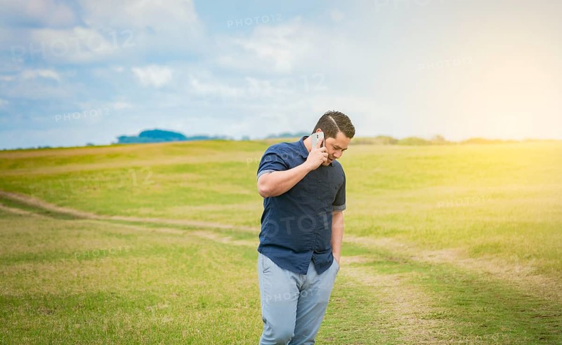 Person with his cell phone in the field talking on the phone