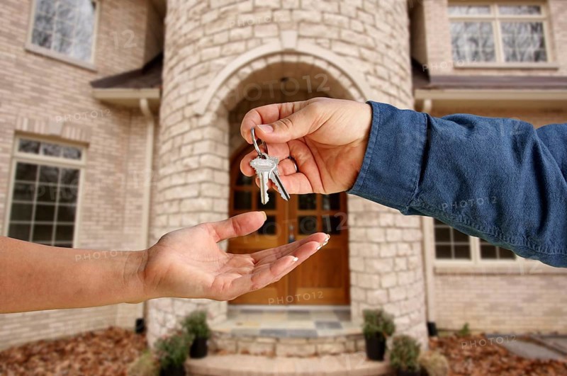 Handing over the house keys in front of a beautiful new home